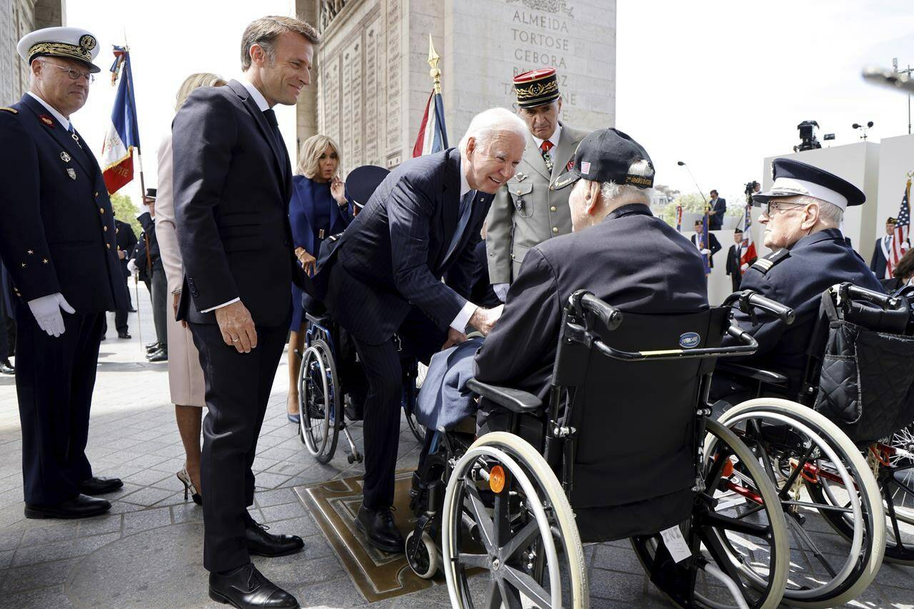 French President Emmanuel Macron, second left, and US President Joe Biden speak to French WWII veteran Jacques Levis, who landed on Utah beach on D-Day alongside US troops, during a ceremony at the Arc de Triomphe, Saturday June 8, 2024 in Paris. President Joe Biden is being feted by French President Emmanuel Macron with a state visit Saturday, as the two allies aim to show off their partnership on global security issues and move past trade tensions. (Ludovic Marin, Pool via AP)