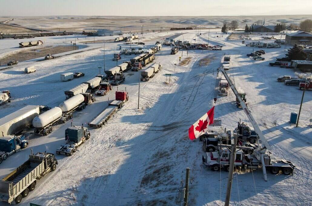 A truck convoy of anti-COVID-19 vaccine mandate demonstrators block the highway at the busy Canada-U.S. border crossing in Coutts, Alta., Wednesday, Feb. 2, 2022. THE CANADIAN PRESS/Jeff McIntosh