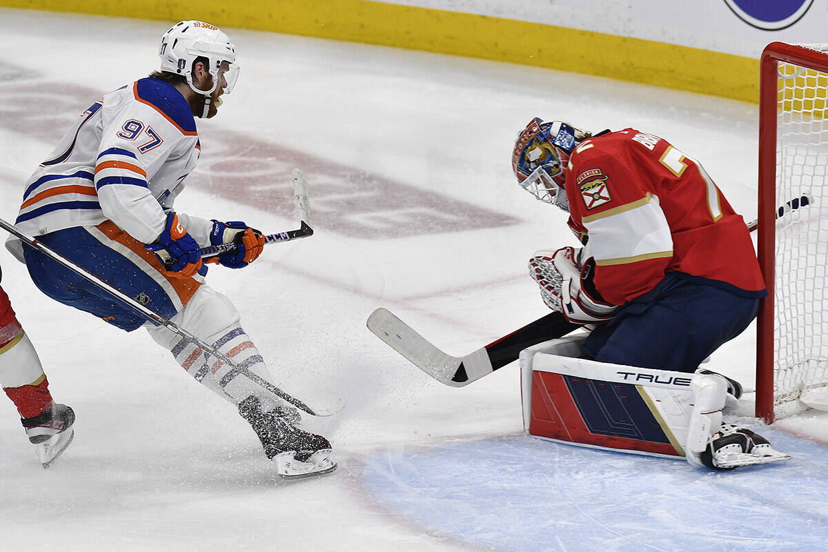 Florida Panthers goaltender Sergei Bobrovsky, right, stops a shot on goal by Edmonton Oilers centre Connor McDavid (97) during the third period of Game 1 of the NHL hockey Stanley Cup Finals, Saturday, June 8, 2024, in Sunrise, Fla. (AP Photo/Michael Laughlin)