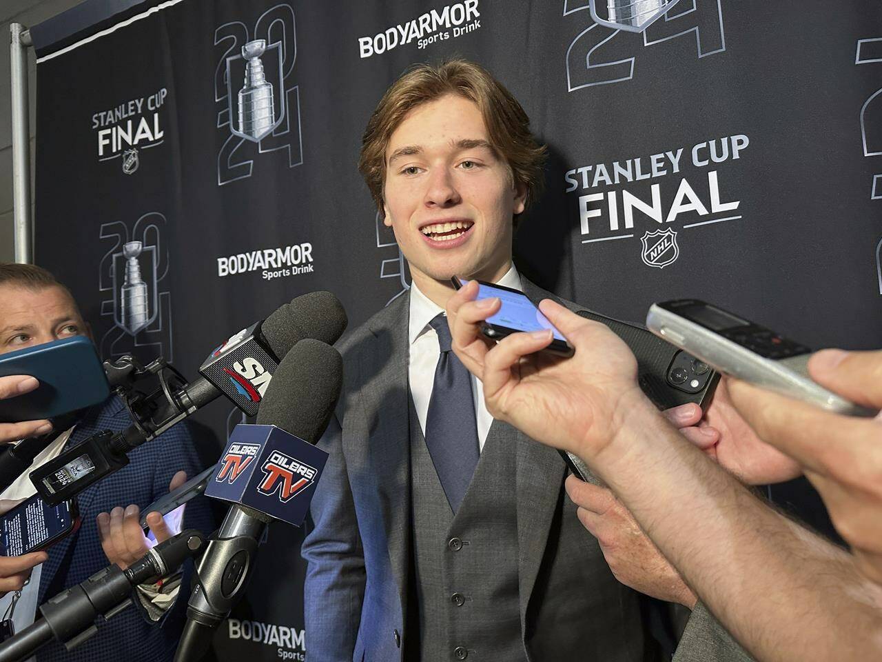 Macklin Celebrini, the expected No. 1 pick in the NHL draft to the San Jose Sharks, speaks with reporters prior to Game 2 of the Stanley Cup Final at Amerant Bank Arena in Sunrise, Florida, Monday, June 10, 2024. (AP Photo/Stephen Whyno)