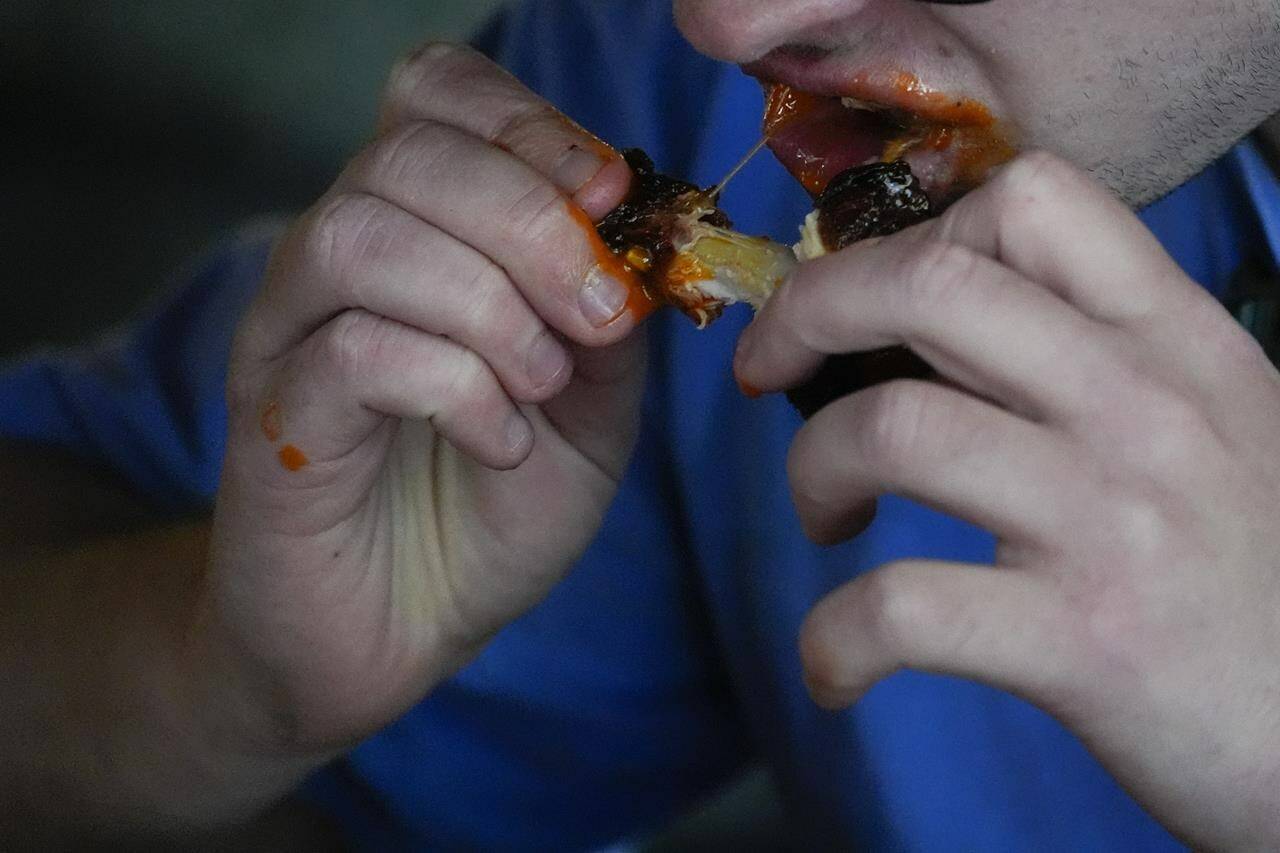A man eats a chicken wing, Wednesday, June 12, 2024, at a barbecue restaurant in Cincinnati. Psychologists have known for years now that men tend to eat more meat than women, but a study of people around the world now reveals that that’s true across cultures. (AP Photo/Joshua A. Bickel)