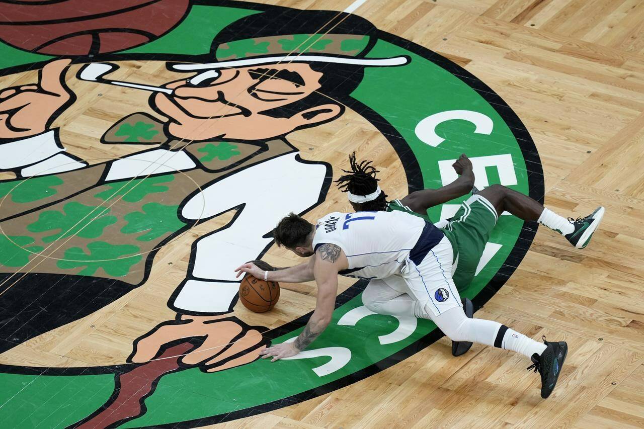 Boston Celtics’ Jrue Holiday, right, and Dallas Mavericks’ Luka Doncic (77) battle for the ball during the first half of Game 5 of the NBA basketball finals, Monday, June 17, 2024, in Boston. (AP Photo/Michael Dwyer)