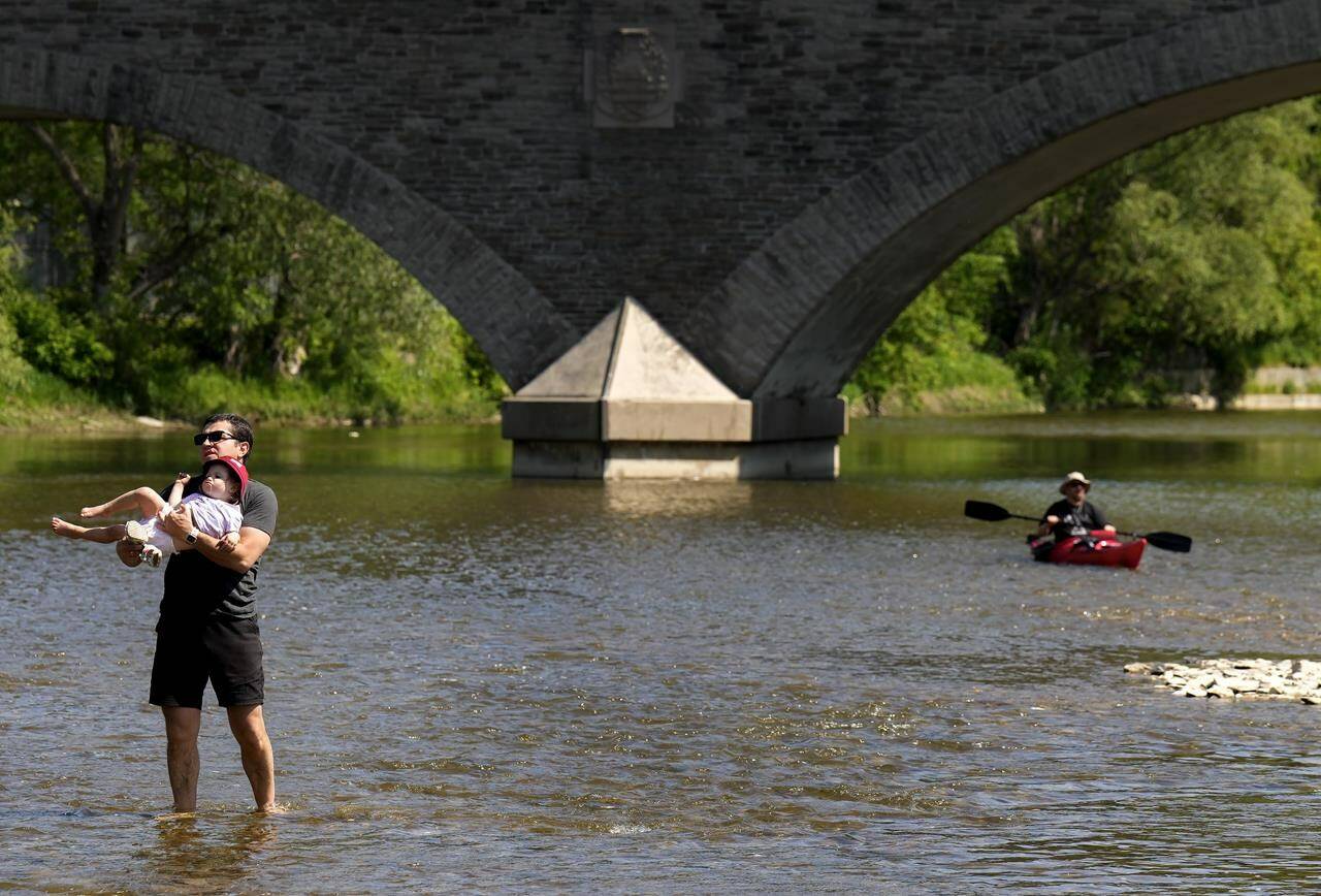 Environment Canada says a heat wave descending on parts of Ontario this week is expected to bring dangerously high temperatures. People cool off along the Humber River in Toronto on Monday, May 29, 2023. THE CANADIAN PRESS/Nathan Denette