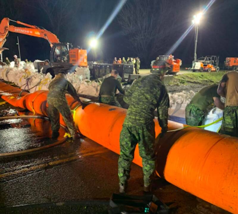 Military personnel help with the placement of a Tiger Dam on Sunday night (Nov. 28) across Highway 1 near Cole Road in Abbotsford. (PHOTO: Abbotsford Police Department)