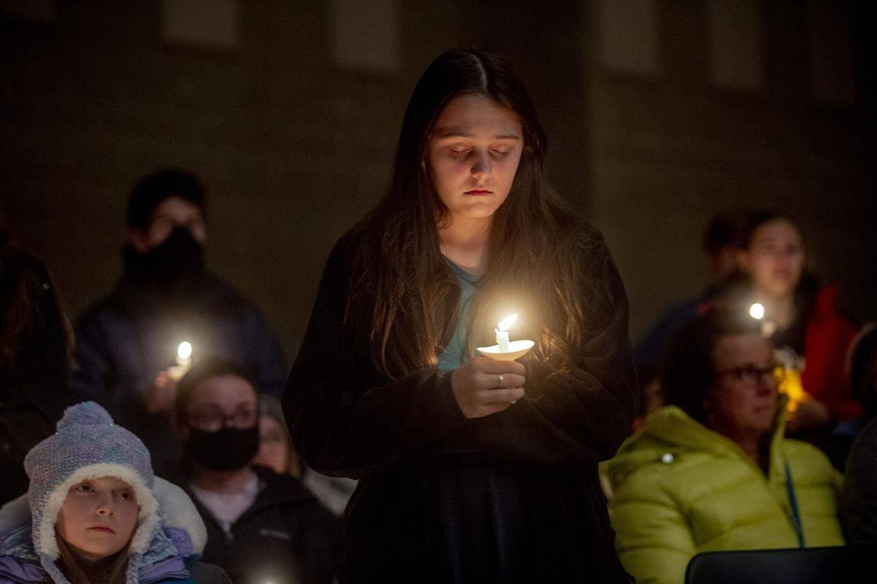 Oxford High School ninth-grader Angelina Stickney stands alongside classmates as they hold candles during a prayer vigil after the Oxford High School school shootings, Tuesday, Nov. 30, 2021, at LakePoint Community Church in Oxford, Mich. (Jake May/The Flint Journal via AP)