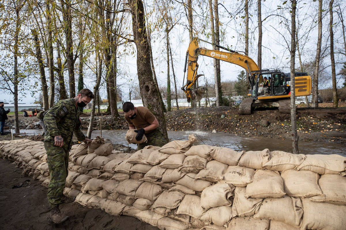 Members of the Canadian Forces build a temporary dike with sandbags behind houses on Clayburn Creek in Abbotsford, B.C., on Wednesday, November 24, 2021. THE CANADIAN PRESS/Darryl Dyck