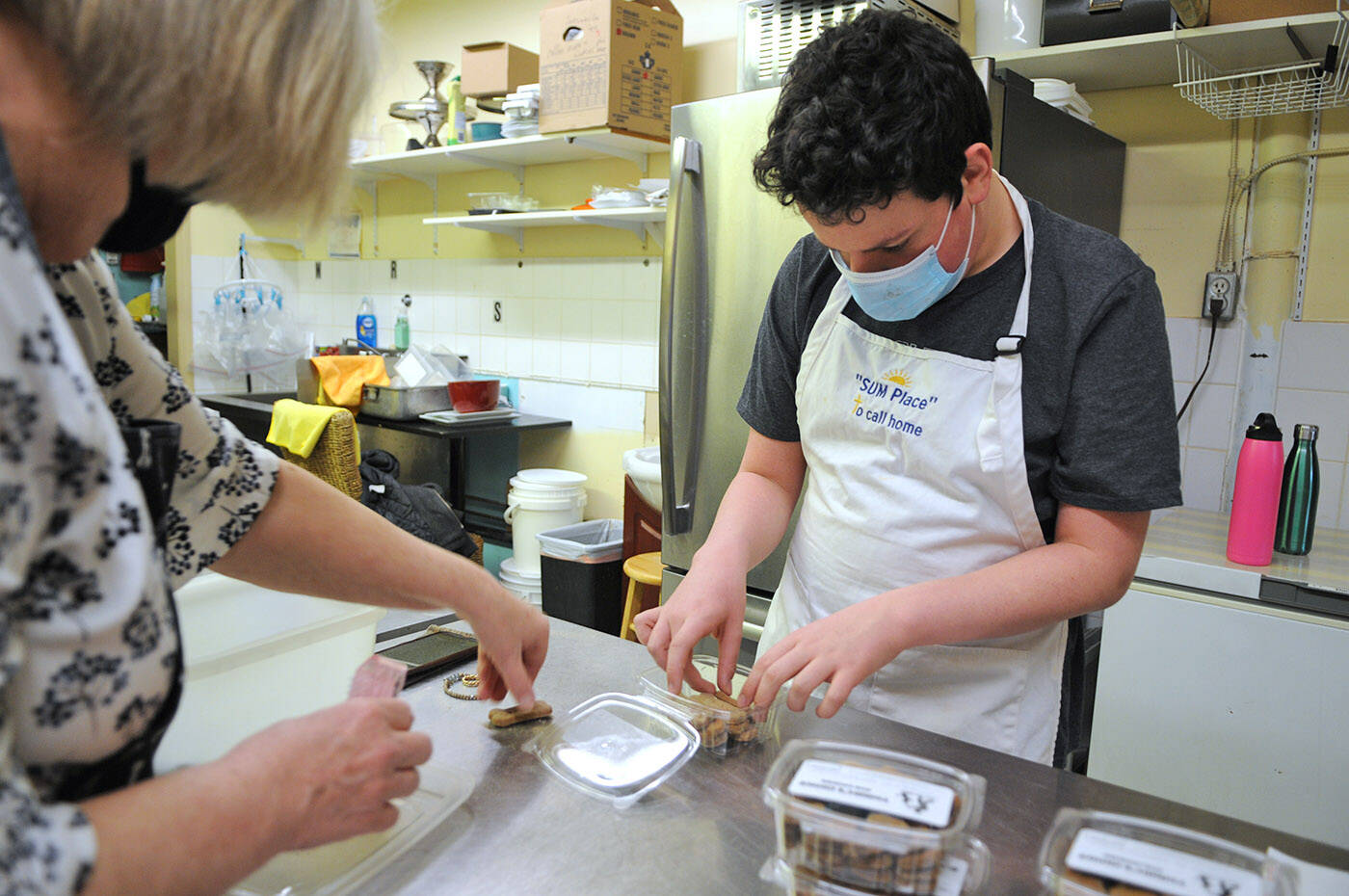 Ryder Newhouse, 14, packages up dog cookies that he helped make with Fergie’s Doggie Delight Pet Bakery co-owner Connie MacDonald on Friday, Dec. 10, 2021. (Jenna Hauck/ Chilliwack Progress)