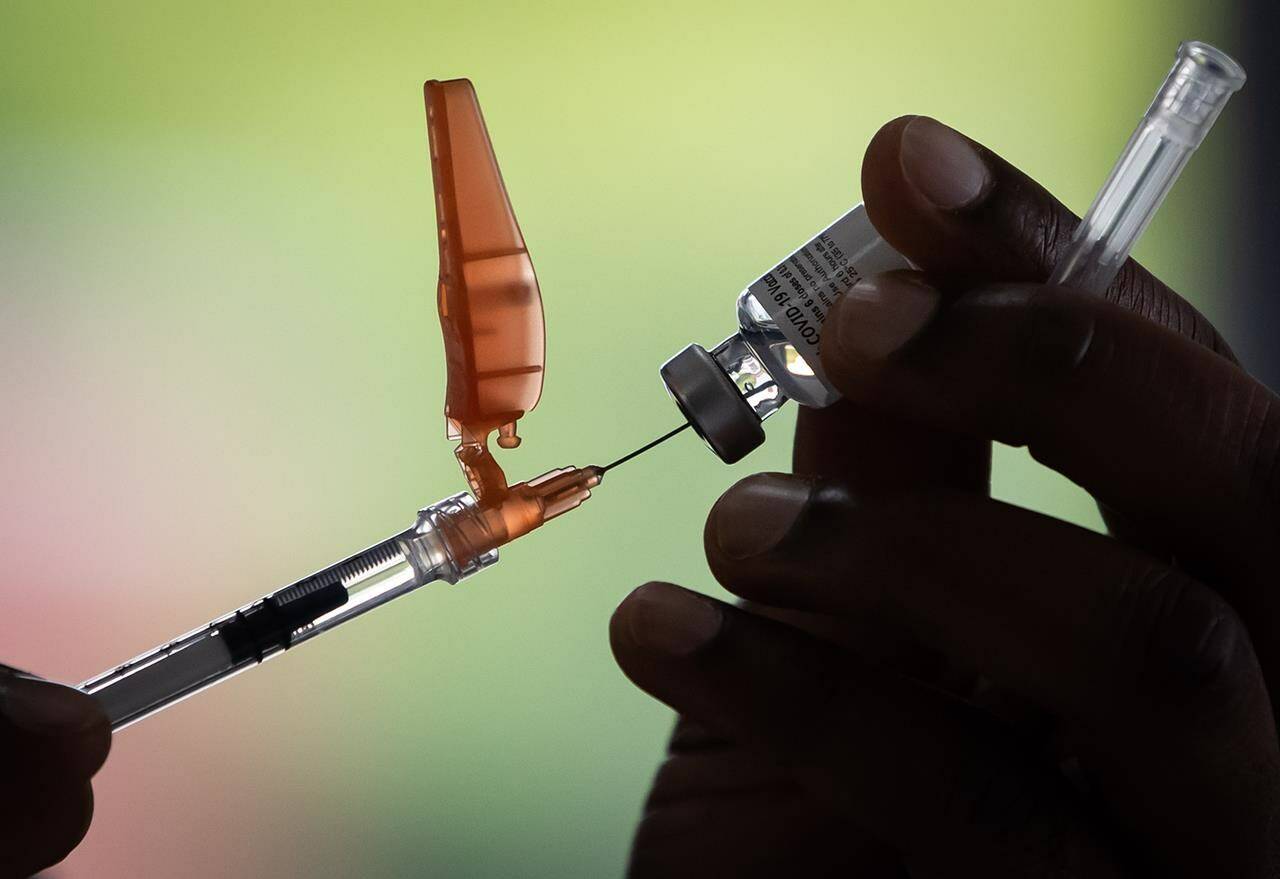 Fraser Health registered nurse Kai Kayibadi draws a dose of the Pfizer COVID-19 vaccine into a syringe at a walk-up vaccination clinic at Bear Creek Park, in Surrey, B.C., on Monday, May 17, 2021. The deadline for British Columbia health care workers to be fully vaccinated against COVID-19 is today. THE CANADIAN PRESS/Darryl Dyck