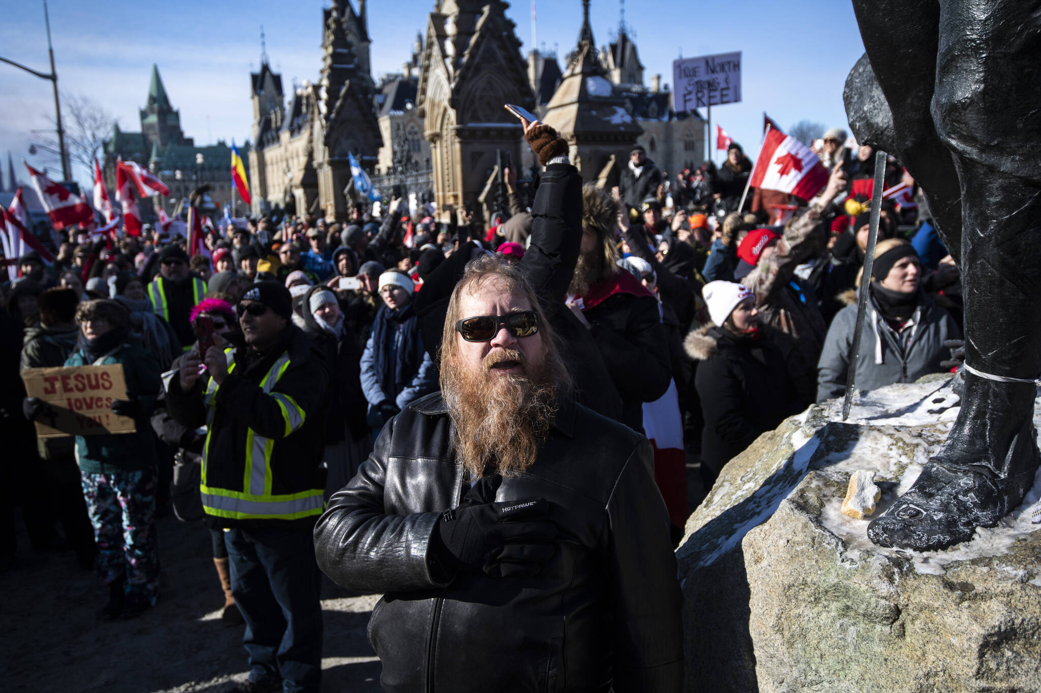 A person holds their hand to their heart during a singing of O Canada during a rally against COVID-19 restrictions on Parliament Hill, which began as a cross-country convoy protesting a federal vaccine mandate for truckers, in Ottawa on Sunday, Jan. 30, 2022. THE CANADIAN PRESS/Justin Tang