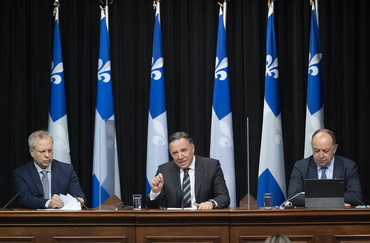 Quebec Premier Francois Legault, centre, speaks during a news conference on the COVID-19 pandemic, Tuesday, February 1, 2022 at the legislature in Quebec City. Legault is flanked by Luc Boileau, Quebec interim director of National Public Health, left, and Quebec Health Minister Christian Dube. Francois Legault says he is abandoning his threat to tax the unvaccinated. THE CANADIAN PRESS/Jacques Boissinot