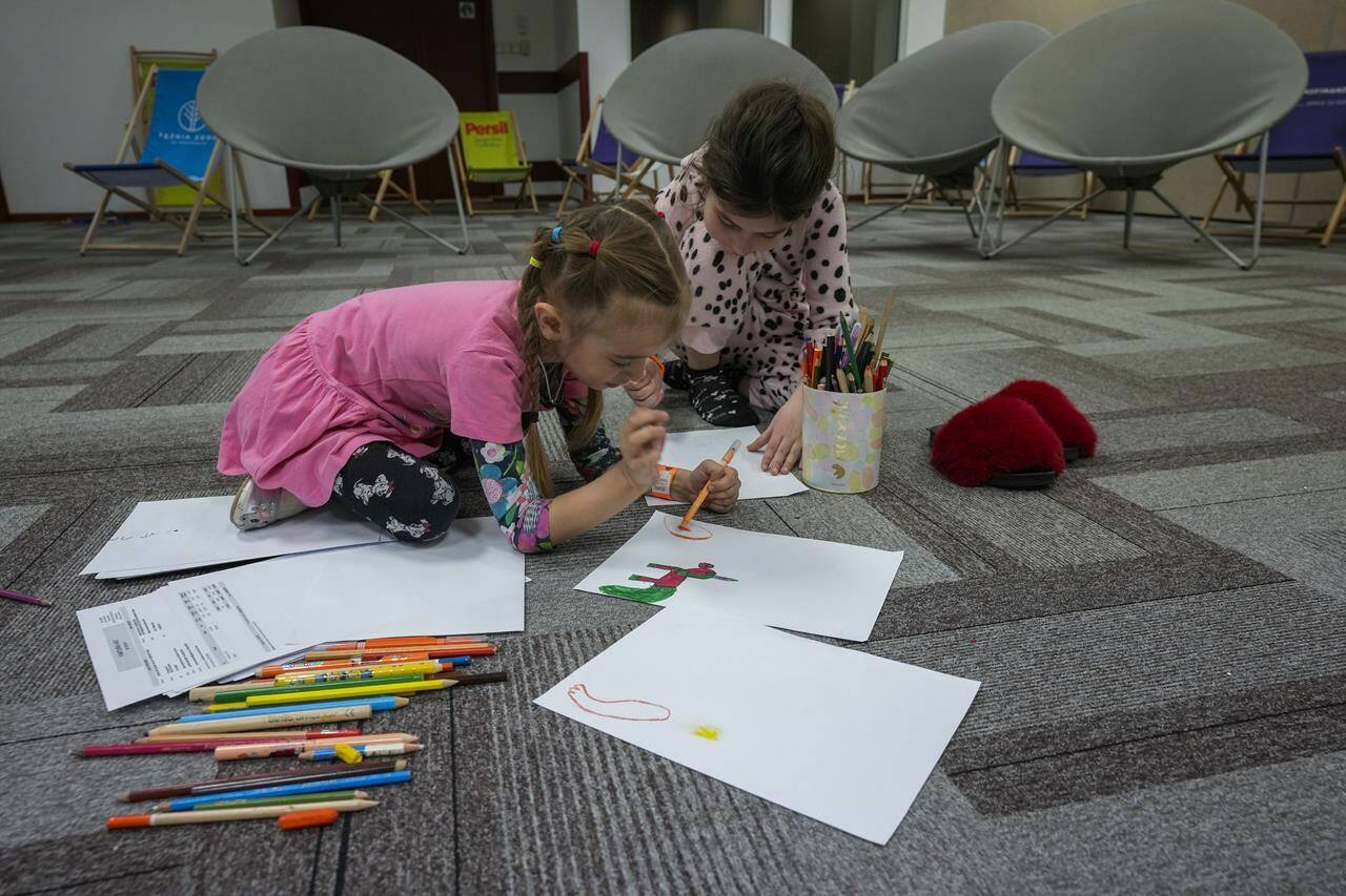 Ukrainian children, who fled from war in Ukraine, draw in a reception center, where they are staying with their mothers in Warsaw, Poland, on Tuesday, March 15, 2022. (AP Photo/Czarek Sokolowski)