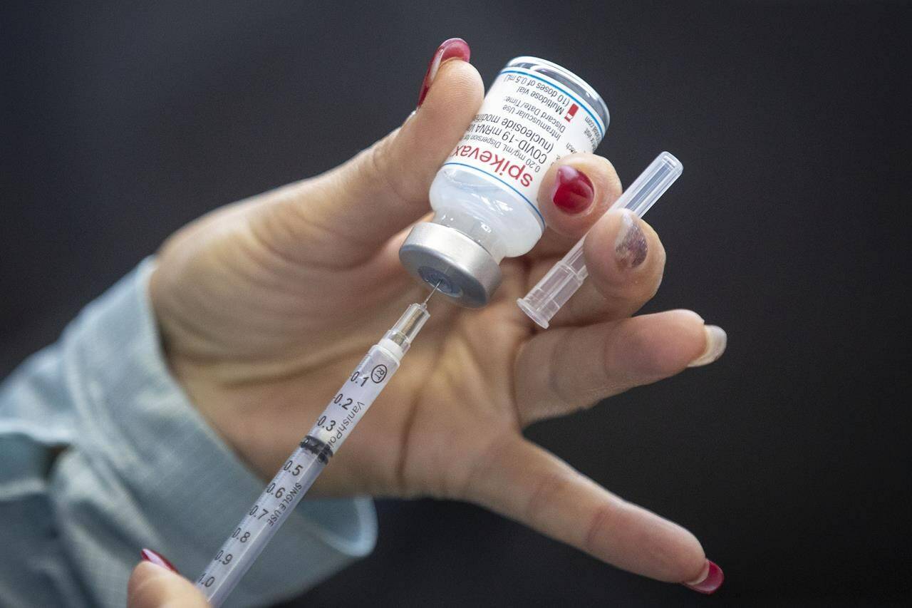 A person draws out Moderna vaccine during a drive through COVID-19 vaccine clinic at St. Lawrence College in Kingston, Ontario, on Sunday January 2, 2022. American vaccine maker Moderna will announce Friday it intends to build its promised Canadian production facility in the Montreal area.  THE CANADIAN PRESS/Lars Hagberg