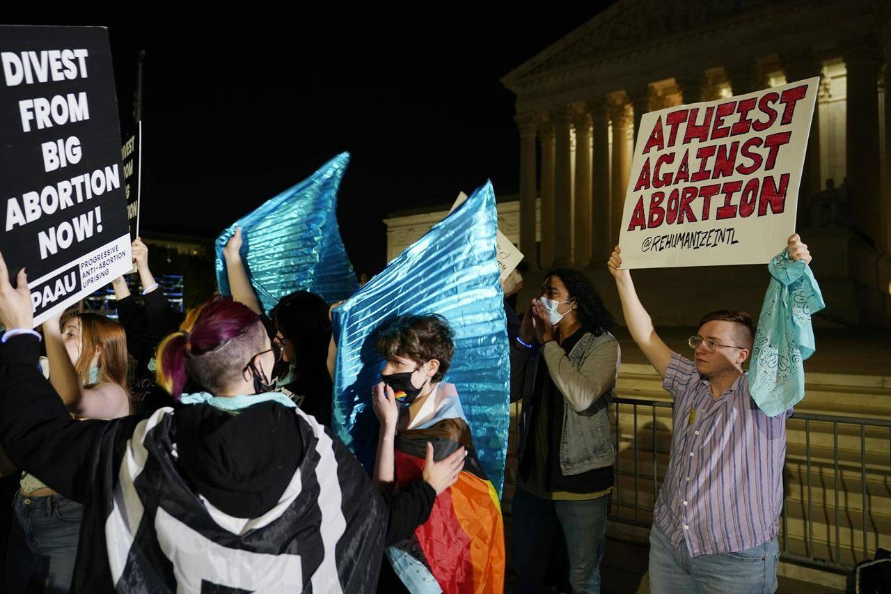 A crowd of people gather outside the Supreme Court, Monday night, May 2, 2022 in Washington. A draft opinion circulated among Supreme Court justices suggests that earlier this year a majority of them had thrown support behind overturning the 1973 case Roe v. Wade that legalized abortion nationwide, according to a report published Monday night in Politico. It's unclear if the draft represents the court's final word on the matter. The Associated Press could not immediately confirm the authenticity of the draft Politico posted, which if verified marks a shocking revelation of the high court's secretive deliberation process, particularly before a case is formally decided. (AP Photo/Alex Brandon)