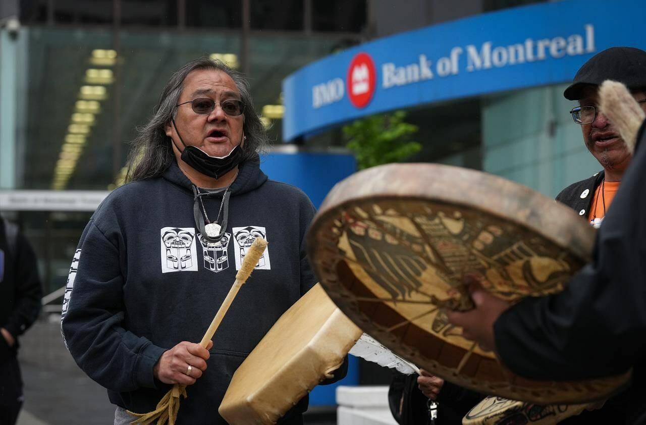 Maxwell Johnson, a Heiltsuk First Nation member who was arrested alongside his granddaughter as they were trying to open an account at the Bank of Montreal, sings and drums outside the bank’s main branch before a news conference in Vancouver, on May 5, 2022. THE CANADIAN PRESS/Darryl Dyck