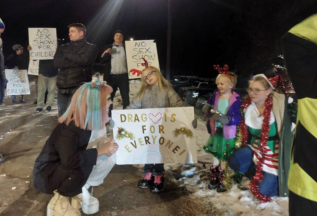 Graeme Flannigan holding a sign that reads ‘no sex for children’ behind a group of children and their mom who attended the Holiday drag show and drag performer Toddy (Jacqueline Gelineau/Capital News)