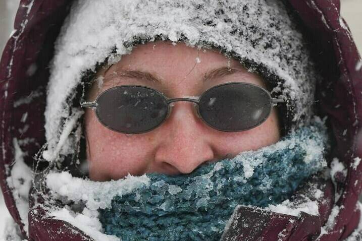 Katrina Hosley is covered in a crust of snow as she uses her snowblower for the fourth time in one morning during a snowstorm in Sioux Falls, S.D., on Tuesday, Jan. 3, 2023.(Erin Woodiel/The Argus Leader via AP)