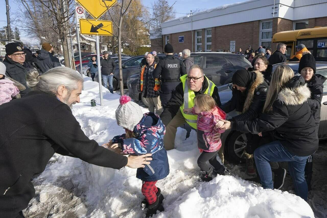 Parents and their children are loaded onto a warming bus as they wait for news after a bus crashed into a daycare centre in Laval, Que., Wednesday, Feb. 8, 2023. THE CANADIAN PRESS/Ryan Remiorz