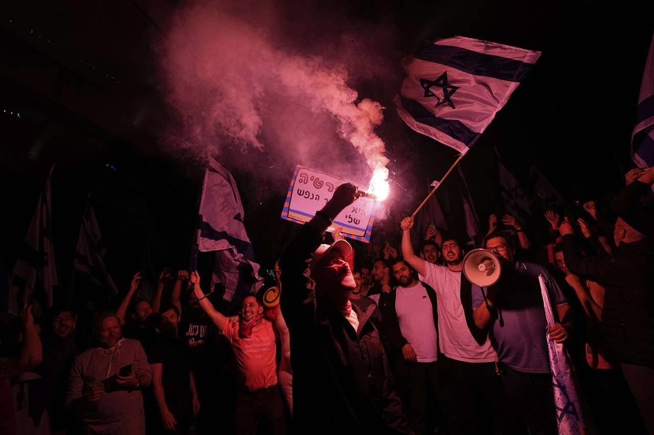 Israelis opposed to Prime Minister Benjamin Netanyahu’s judicial overhaul plan block a highway during a protest after the Israeli leader fired his defense minister, in Tel Aviv, Israel, Monday, March 27, 2023. Defense Minister Yoav Gallant had called on Netanyahu to freeze the plan, citing deep divisions in the country and turmoil in the military. (AP Photo/Ohad Zwigenberg)