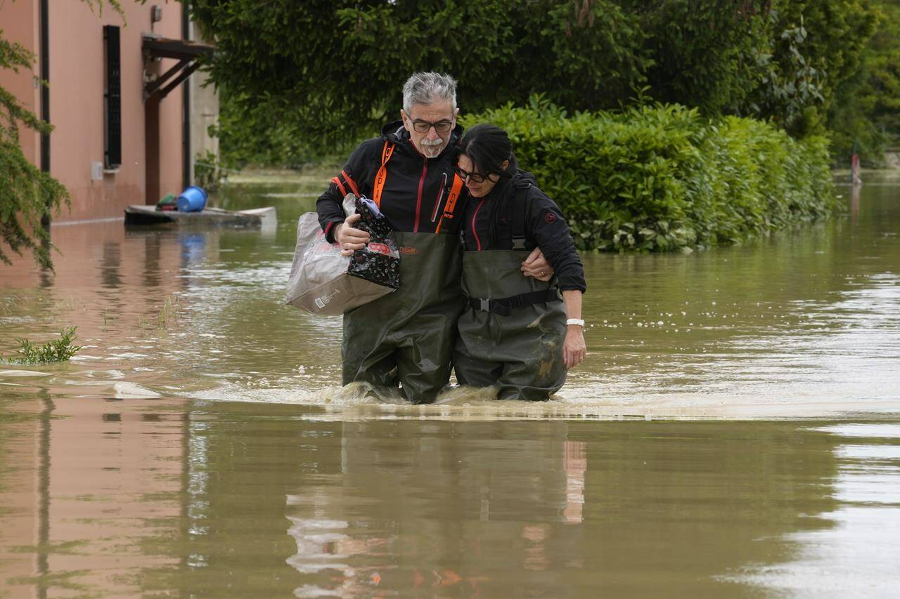 FILE - A couple walk through a flooded road of Lugo, Italy, May 18, 2023. The floods that sent rivers of mud tearing through towns in Italy’s northeast are another soggy dose of climate change’s all-or-nothing weather extremes, something that has been happening around the globe, scientists say. (AP Photo/Luca Bruno, File)
