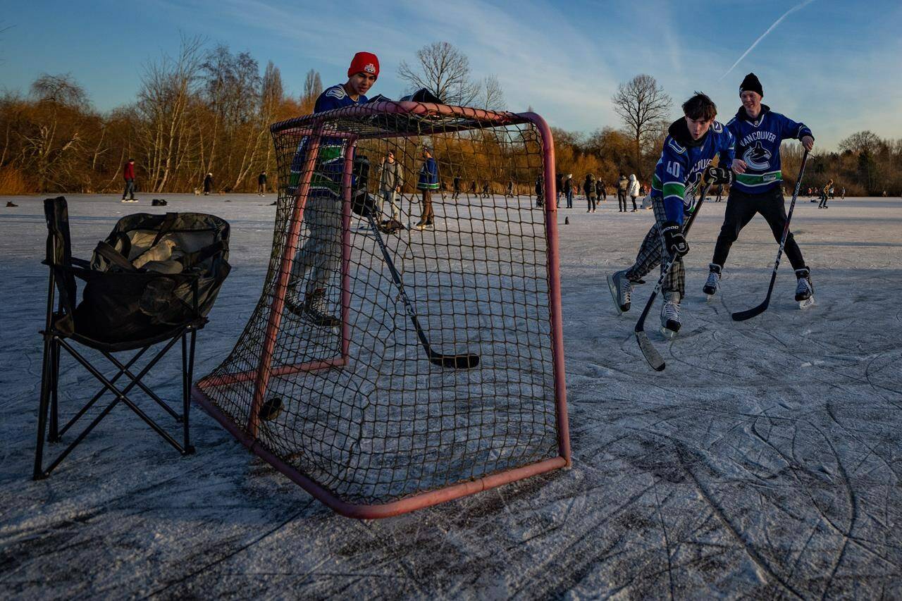 People dressed in Vancouver Canucks jerseys play hockey on frozen Trout Lake amid a cold snap in Vancouver on Sunday, Jan. 14, 2024. THE CANADIAN PRESS/Ethan Cairns