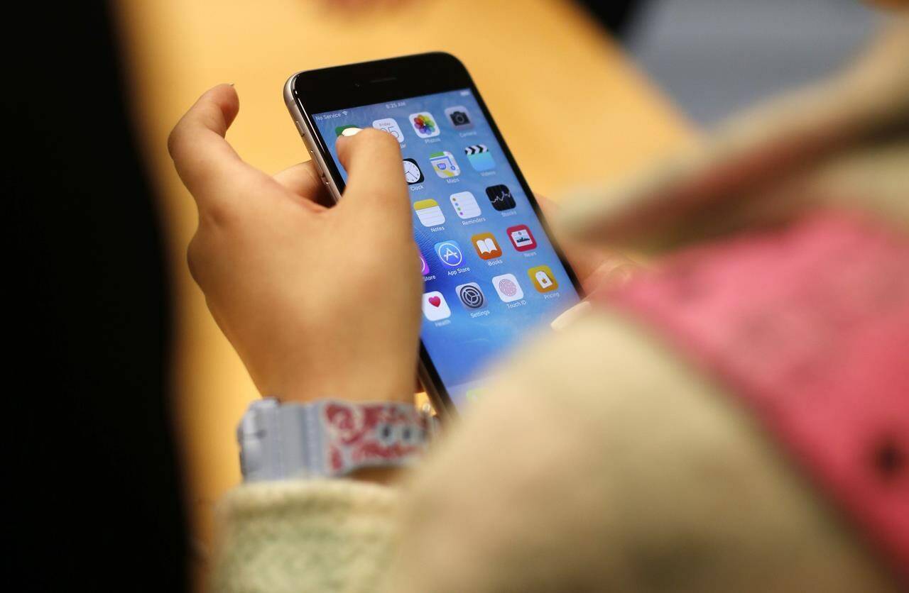 FILE - A child holds an iPhone at an Apple store on Sept. 25, 2015 in Chicago. Parents — and even some teens themselves — are growing increasingly concerned about the effects of social media use on young people. (AP Photo/Kiichiro Sato, File)